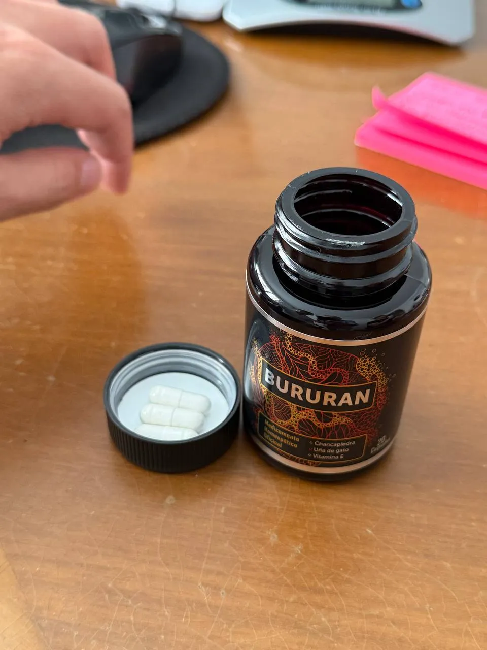 Frasco de Bururan abierto con tres cápsulas blancas sobre la tapa