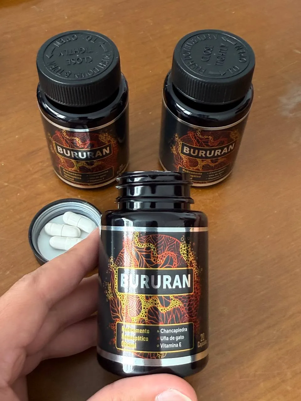 Tres frascos de Bururan y una mano sosteniendo uno abierto